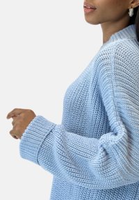 Hellblauer gestrickter Pullover mit gerippter Textur, weitem Bund und Rundhalsausschnitt, der einen lässigen Schnitt und detaillierte Nähte zeigt.