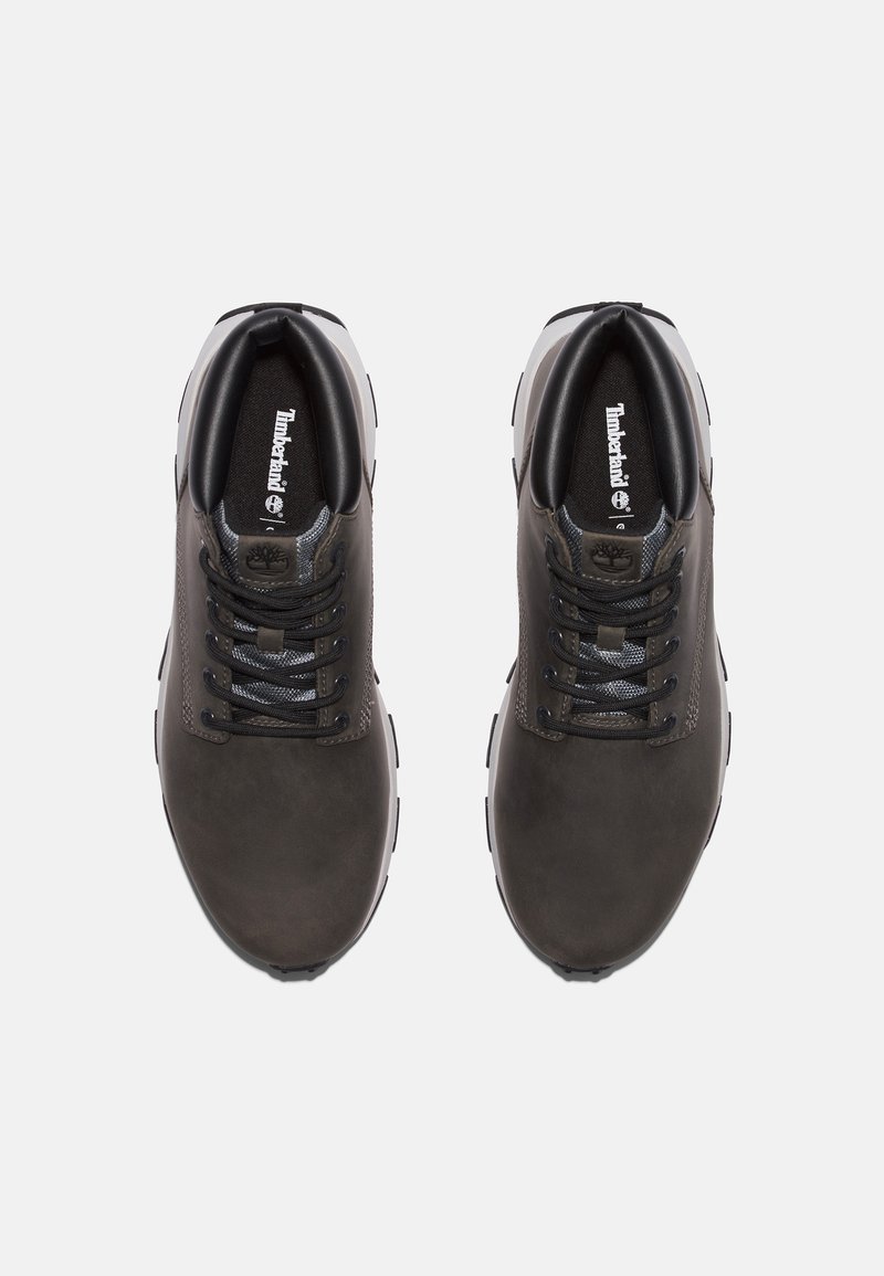 Zapatillas de cuero gris oscuro con detalles en negro, puntera redonda, lengüeta de malla texturizada y suela blanca contrastante. Logo de Timberland en la plantilla.