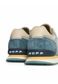 Zapatillas beige y azules con parte superior de cuero texturizado y ante. Presentan una suela de goma en contraste con la marca "HOFF" en blanco.