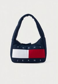 Navy blue shoulder bag with padded strap, front featuring white and red color blocks and "Tommy Jeans" text branding.