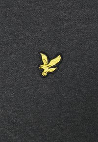 Tessuto grigio scuro con una finitura testurizzata, caratterizzato da un logo di aquila ricamato in giallo sul lato sinistro. Nessun altro motivo o dettaglio presente.