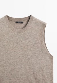 Beige ilman hihoja oleva neule, jossa on pyöreä pääntie, valmistettu pehmeästä neuloksesta. Ominaisuuksiin kuuluu ribbireunus kauluksessa ja kädenteissä, sekä hienovarainen rakenne kauttaaltaan.