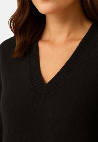 Czarny sweter z dekoltem w serek, z prążkowanym wykończeniem, wykonany z miękkiego, teksturowanego materiału, o luźnym kroju i minimalistycznym designie.