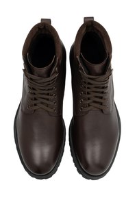 Een paar donkerbruine leren veterschoenen tot de enkel met gewatteerde kraag en zwarte rubberen zolen, vanuit bovenaf bekeken op een witte achtergrond.