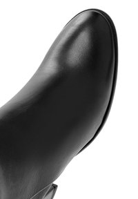 Zwarte leren enkellaars met een ronde neus, een gladde textuur en een lage hak. Het ontwerp heeft minimale stiksels en geen zichtbare hardware.