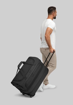 Borsa da viaggio nera con ruote, dotata di doppi manici, dettagli testurizzati e chiusura con zip. Superficie liscia, grande capacità e ruote robuste per il trasporto.