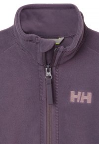 Fleece bunda ve tmavě fialové barvě s vyšším límcem a plným zipem. Obsahuje malé logo světle fialové barvy na prsou a má jemnou texturu.