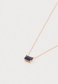 Collana delicata in oro rosa con ciondolo a forma rettangolare di pietra blu scuro scintillante impostato in una montatura a quattro griffe, su uno sfondo chiaro.