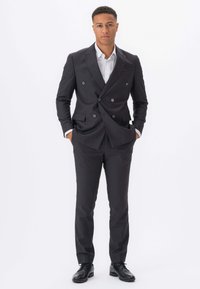 Mørkegrå dobbeltradet jakkesæt med skræddersyet pasform, hvid skjorte underneath og sorte sko. Glat stof med en subtil glans.