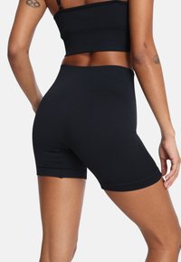 Crne biciklističke kratke hlače visokog struka, izrađene od glatkog, rastezljivog materijala. Imaju prilagođen dizajn, s čistu, bešavnu traku u struku i porub.