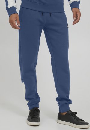 Blue sweatpants in cotton blend material; tapered fit with an elastic waistband, featuring a white accent on the side and adjustable drawstrings.