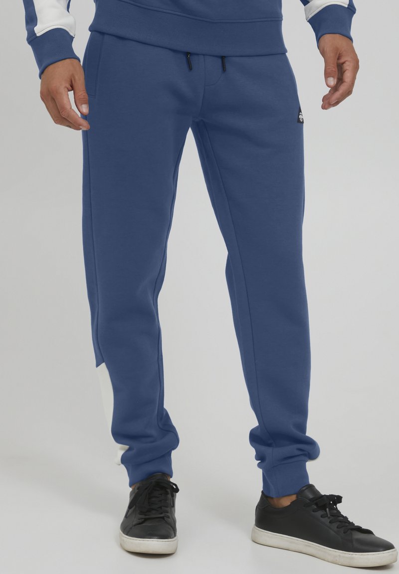 Blue sweatpants in cotton blend material; tapered fit with an elastic waistband, featuring a white accent on the side and adjustable drawstrings.