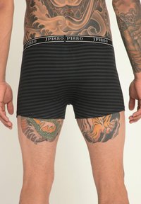 Boxer briefs à rayures noires avec une large ceinture élastique portant l'inscription "JP1880." Présente des tatouages de dragon et de tigre visibles sur les jambes.