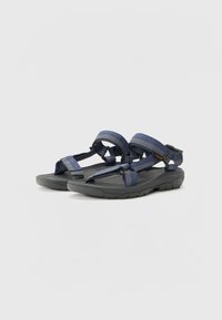 Marineblå sandaler med justerbare stropper, strukturert stoff og en polstret svart såle med robust mønster for grep og stabilitet.