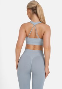 Gray sports bra with a racerback design and textured finish, paired with high-waisted gray leggings featuring seamless construction.