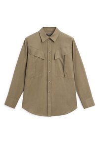 Long-sleeve button-up shirt in olive green fabric, featuring a collared neckline, two large chest pockets, and a curved hem. Silver buttons present.