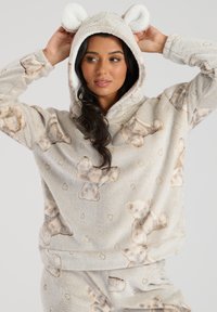Fleece-Hoodie in hellbeige mit Teddy-Muster und Herzen, ausgestattet mit einer weich gefütterten Kapuze mit flauschigen Ohren und entspanntem Ärmel-Fit.