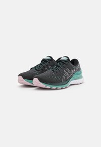 Baskets de sport noires avec dessus en mesh, accents turquoise et semelle rose. Présentent une surface texturée, un talon renforcé et des lacets contrastés.