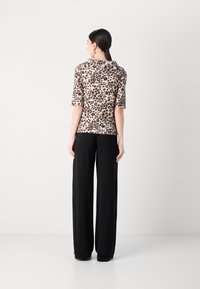 Leopard print, fitted top with short sleeves, paired with high-waisted black wide-leg trousers, smooth fabric, minimalistic design.