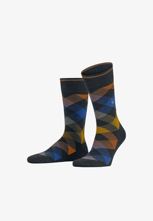 Dunkel gemusterte Socken mit einem Rautendesign in Blau, Orange, Gelb und Grau, die mit einem sichtbaren Logo auf einer Socke präsentiert werden.