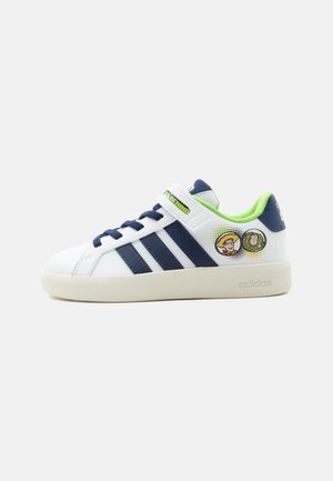 Λευκό sneaker Adidas με ναυτικό μπλε ρίγες, πράσινη επένδυση, με τους χαρακτήρες Woody και Buzz από το «Toy Story» τυπωμένους στο πλάι και λουράκι με βέλκρο.