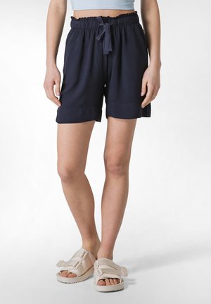 Mørkeblå, knæ-lange shorts med elastisk talje og snøre. Glat materiale, afslappet pasform, opsmøg på kanten, parret med beige sandaler.