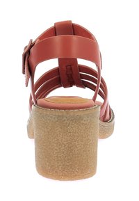 Sandalias de tacón de cuero marrón con múltiples tiras y un tacón redondeado y texturizado en tono beige. Presenta una hebilla en el lateral para un ajuste regulable.