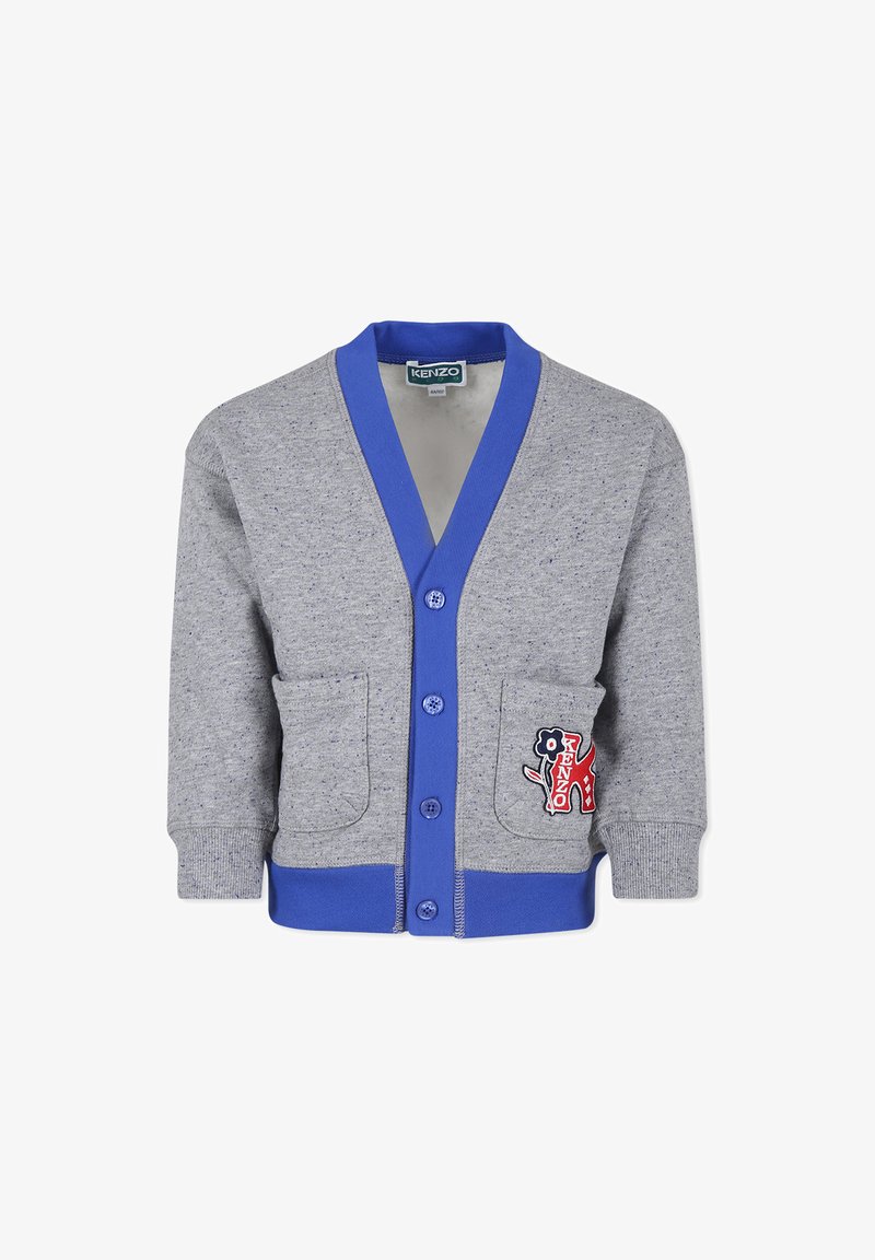 Cardigan gris en tissu doux, avec un col en V côtelé bleu, fermeture à boutons, deux poches avant et une patch décoratif.