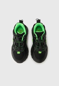 Μαύρα αθλητικά παπούτσια με επάνω μέρος από δίχτυ, πράσινες λεπτομέρειες και κορδόνια, και ανθεκτική σόλα από καουτσούκ. Διαθέτουν κλείσιμο με κουμπί για εύκολη ρύθμιση.
