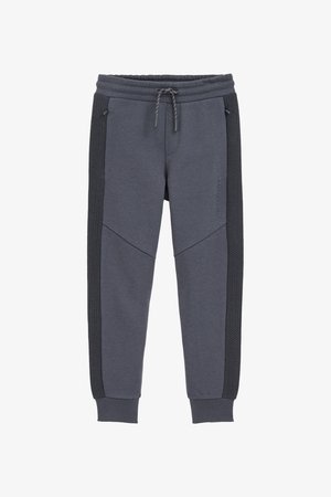 Pelēki sporta bikses ar elastīgu jostu, auklu un faktūrētām melnām sānu daļām ar ģeometrisku rakstu. Izgatavotas no mīksta auduma.