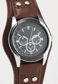 Analog chronograph watch with a black dial, silver hands, and brown leather strap featuring contrasting stitching and metal studs.