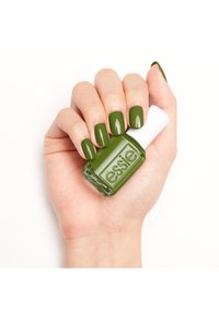 Groene nagellak in een rechthoekige fles met een witte dop, vastgehouden in een hand met glanzende groene nagels, alles op een witte achtergrond.