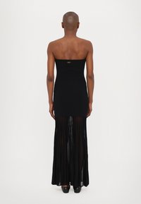 Black strapless maxi dress featuring a fitted top and a pleated sheer skirt. The dress has a branding detail at the back.