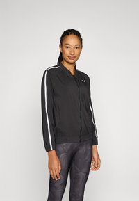 Black windbreaker jacket with a zip front closure, white stripes on sleeves, and an elastic waistband. Lightweight fabric.