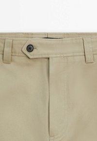 Khaki pants waistband with belt loops and a black button securing a fabric tab closure.
