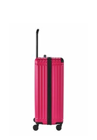Valigia rigida di colore rosa brillante con texture rigata verticale, zip nera e quattro ruote girevoli per la mobilità. Manico telescopico nero.
