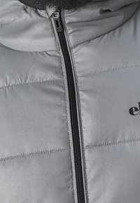 Graue Steppweste mit glatter Oberfläche, schwarzem Reißverschluss und Logodetail auf der Vorderseite. Verfügt über horizontale gesteppten Abschnitte zur Isolierung.