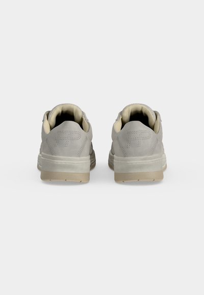 Paire de baskets gris clair vues de dos avec des collerettes rembourrées et un logo cousu sur chaque languette de talon sur un fond clair uni.