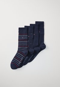 Quatre paires de chaussettes marines : une avec des rayures rouges et blanches, trois unies marines avec de légers accents de logo et une texture lisse.