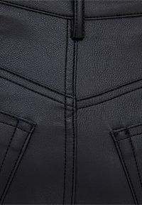 Matériau en cuir synthétique noir avec une surface texturée, présentant des motifs de couture angulaires et deux poches avant.