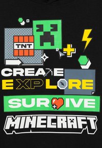 Black t-shirt featuring vibrant graphics, including "CREATE," "EXPLORE," and "SURVIVE" in bold colors, along with Minecraft-themed icons.