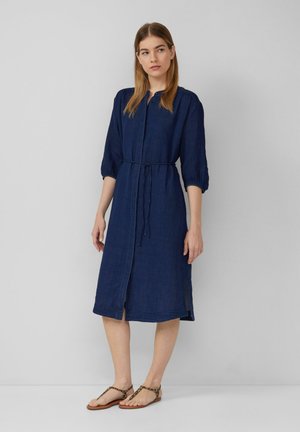 Abito blu navy a lunghezza ginocchio con abbottonatura frontale, maniche arricciate, vita con fiocco e spacchi laterali; realizzato in un tessuto leggero.