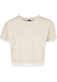 Krémový krátký rukávový crop top s kulatým výstřihem, se kontrastním bílým lemem. Vyrobeno z jemné, hladké bavlněné tkaniny.