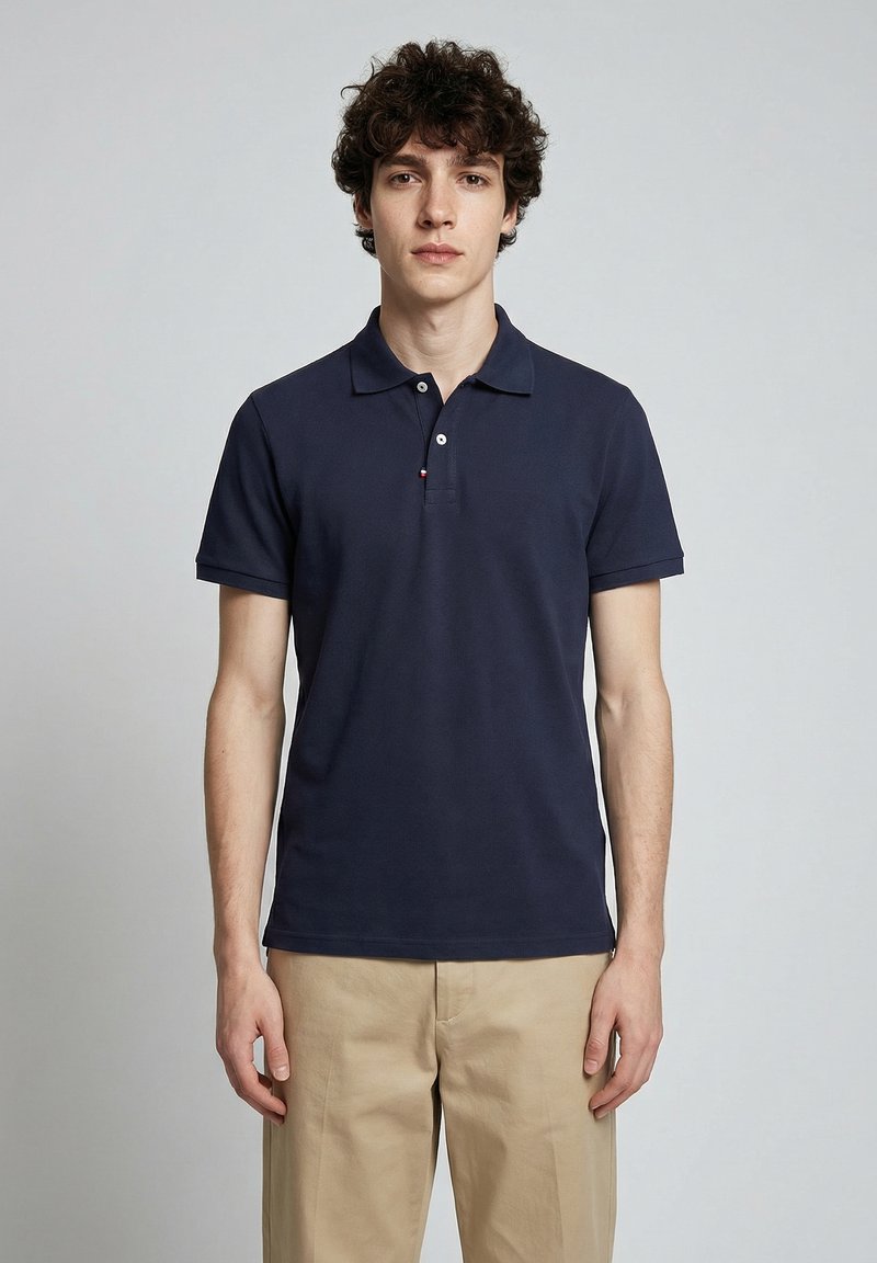 Polo bleu marine en coton texturé, avec un col classique, des manches courtes et une patte de boutonnage à trois boutons ornée d'un logo.