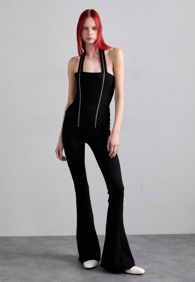 Black jumpsuit with a square neckline, flared legs, and a visible zipper detail running down the front. Soft, stretchy material.