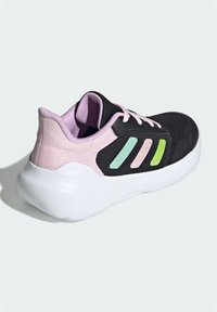Baskets de sport noires avec des accents en mesh rose, trois rayures colorées (verte, rose, bleue) sur le côté, et une semelle blanche rembourrée.