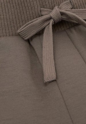 Pantaloni maro cu talie înaltă, largi, prevăzuți cu o bandă din material striat și o fundă din același material. Textură netedă, culoare uniformă. Croială lejeră în ansamblu.