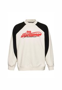 Hvit hettegenser med svarte raglanermer, med et stort rødt "99 Rockwear" grafisk trykk på framsiden. Myk stoff med ribbede mansjetter.