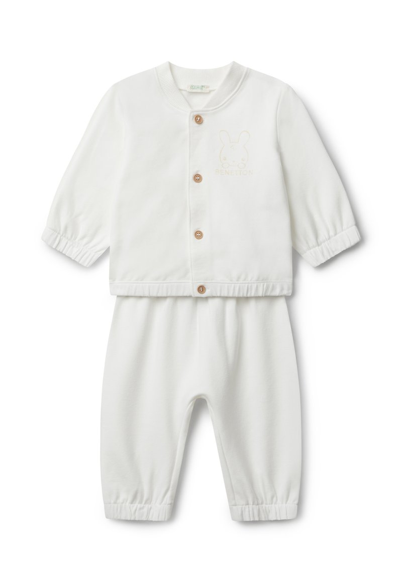 Bílý dvoudílný outfit pro miminko, který obsahuje sako na patentky s elastickými manžetami a kalhoty se shodným elastickým pasem. Vyšívané detaily králíčka.