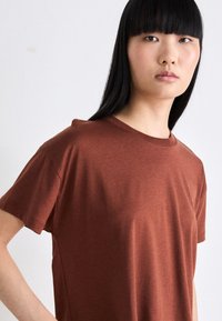 Koperkleurig kortemouwenshirt van zachte stof, met een ronde hals en een ontspannen pasvorm, met subtiele textuur en zonder zichtbare patronen.